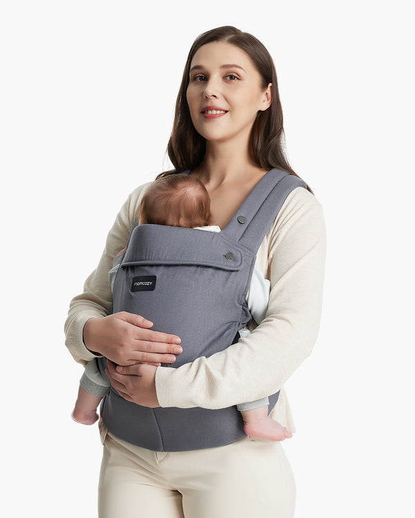 Woman wearing a gray Momcozy baby carrier, holding an infant comfortably.