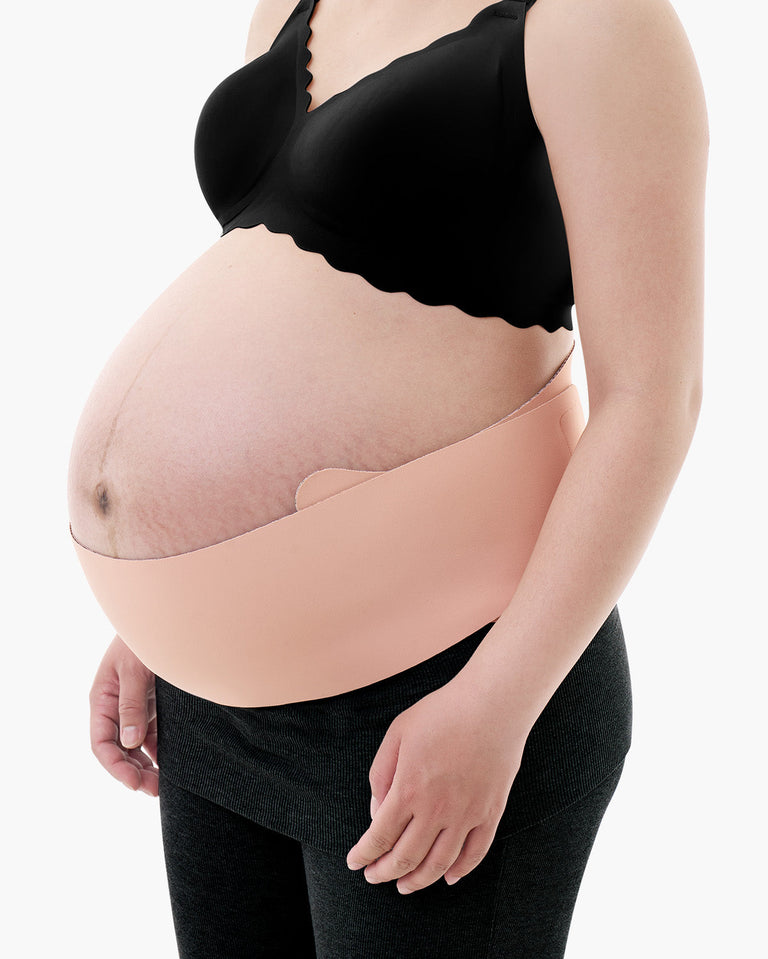 Translation missing: pl.Light beige Momcozy Maternova belly band shown on a pregnant model wearing a black bra and grey leggings