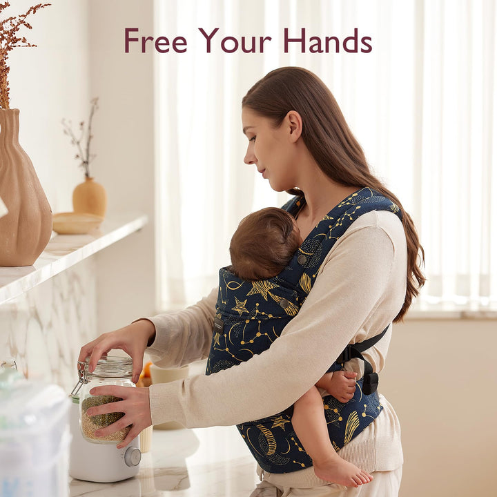 Mom using Baby Carrier Newborn to Toddler in Starry Night design while working in the kitchen. 'Free Your Hands' text at the top.