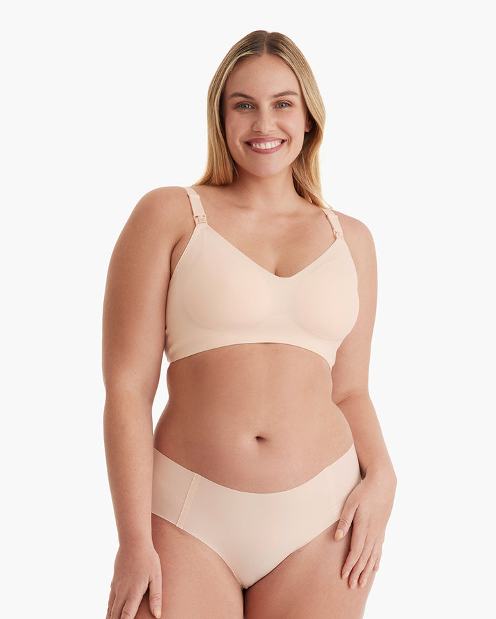 Smiling model in light peach YN21 Ultra Soft Seamless Nursing Bra, showing V-neck, smooth fit, and nursing clips.